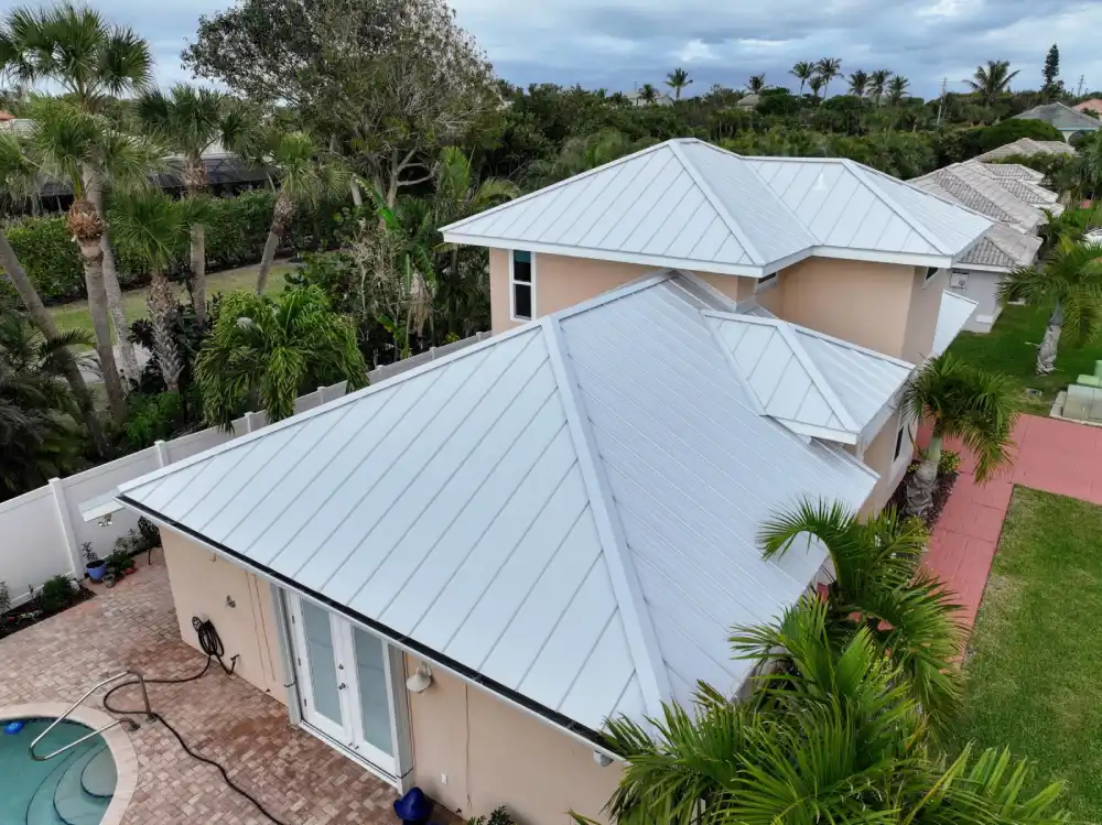 Aerial view of metal-roofed Florida home with surrounding tropical greenery